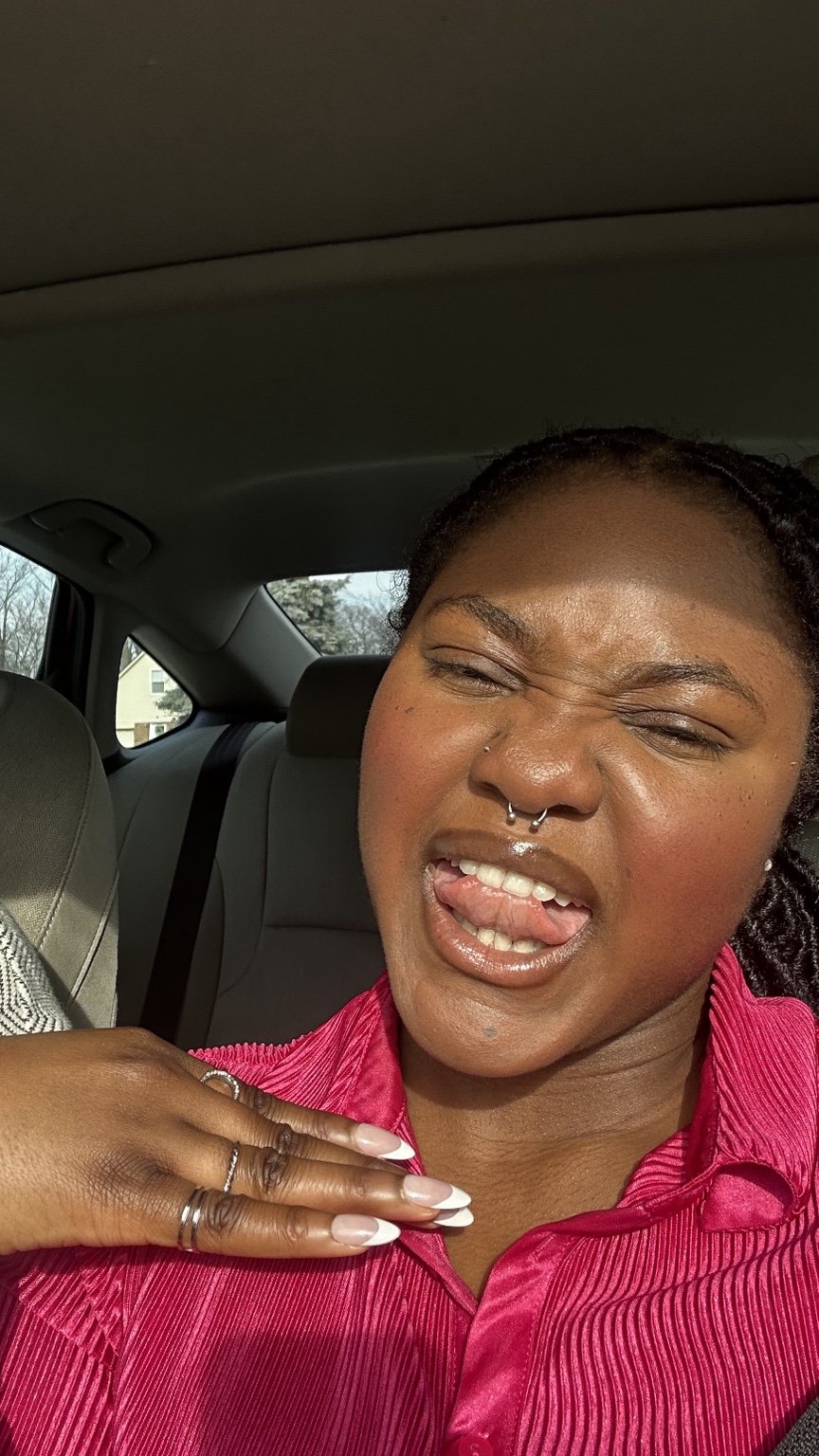 Temi making a playful expression in a bright pink blouse