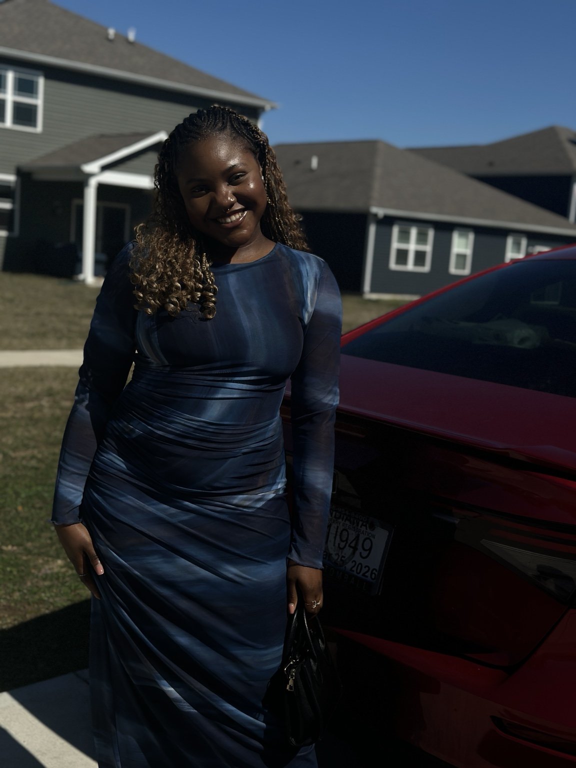 Temi smiling outdoors in a navy blue dress